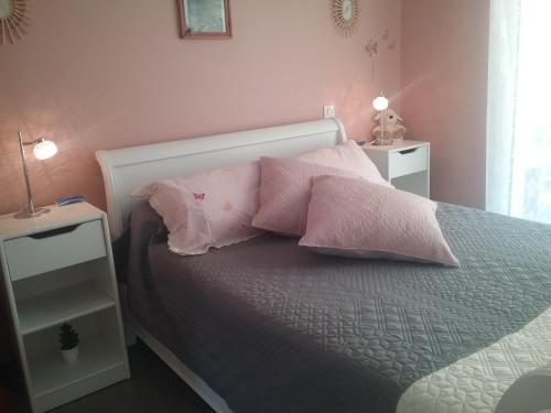 a bed with two pink pillows on top of it at gîte La Valentina, climatisé in Cubjac-Auvézère-Val d'Ans