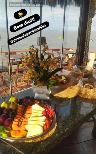 a table with a plate of fruit on a table at Pousada Do Sol Ilha do Mel in Paranaguá