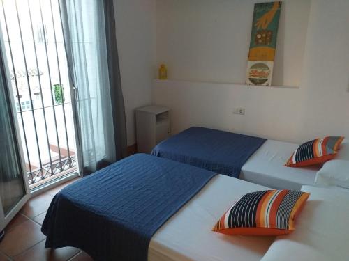 two beds in a room with a window at Adosado tres habitaciones, en Bahía de la Plata, Zahara de los atunes in Zahara de los Atunes