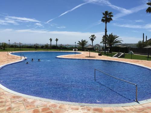 a large blue swimming pool with people in it at Adosado tres habitaciones, en Bahía de la Plata, Zahara de los atunes in Zahara de los Atunes