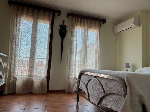 a bedroom with a bed and two windows with curtains at Casa Rivendel - Fantasía, Confort y Naturaleza in Poyales del Hoyo
