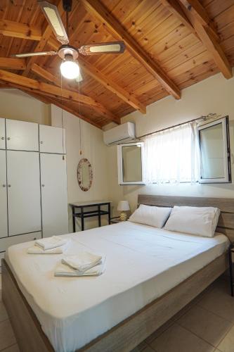 a bedroom with a large white bed with a wooden ceiling at Agios Andreas Beach Villas in Áyios Andréas Messinias