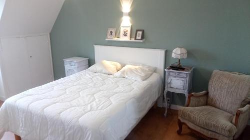 a bedroom with a white bed and a chair at Ploubalay Chambres Cuisine Séjour in Ploubalay