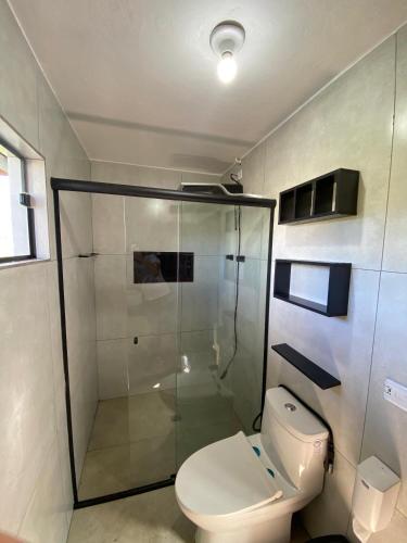 a bathroom with a toilet and a glass shower at POUSO DE ICARO - POUSADA NO CENTRO de PARATY in Paraty