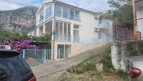 a large white house with blue balconies on a street at Villa Mirijana in Zlatna Obala