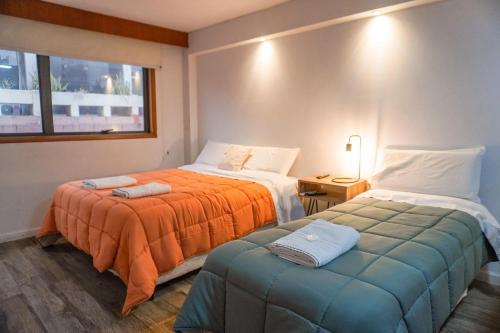 a hotel room with two beds and a ottoman at Departamento 114 - Edificio VILAUT by INMOVE Temporarios in Córdoba