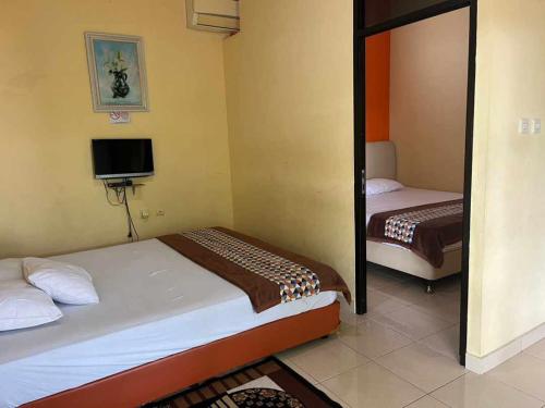 a bedroom with two beds and a tv in it at HOMESTAY RJS Pulau Tidung NWR in Pulau Tidung-besar