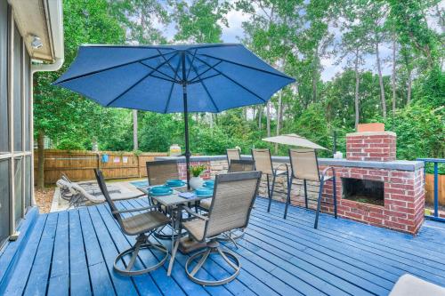 a table and chairs with an umbrella on a deck at New! Pool, Spa, Nature Trails - The Woodlands 4BR Forest Retreat! in Spring