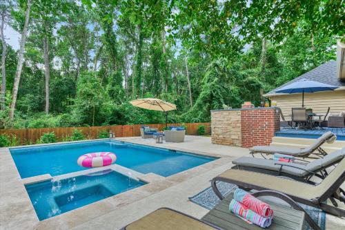 a swimming pool with two chairs and an umbrella at New! Pool, Spa, Nature Trails - The Woodlands 4BR Forest Retreat! in Spring