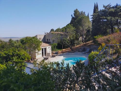 a swimming pool with a house and trees at De l'étang de BAGES au massif de la Clape in Narbonne
