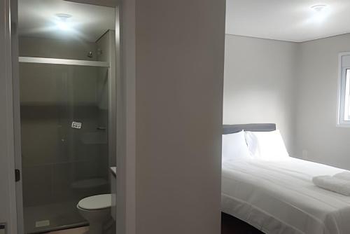 a bedroom with a bed and a bathroom with a shower at Apartamento Central com suite Panazzolo 7 minutos do centro in Caxias do Sul