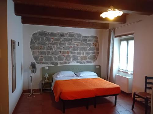 a bedroom with a bed with an orange blanket at Agriturismo Antica Corte in Montatteglia