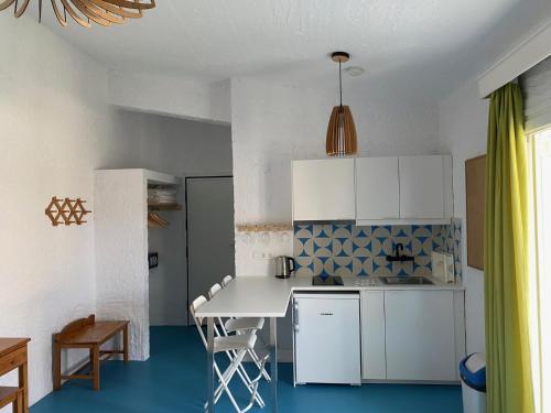スキアトスタウンにあるManolis' Houseの白いキャビネットとテーブルと椅子のあるキッチン