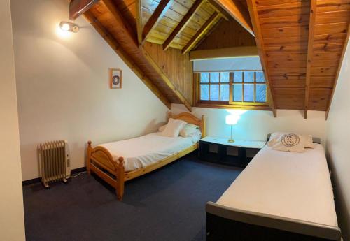 a bedroom with two beds and a table in a attic at Vila Bela in Tigre