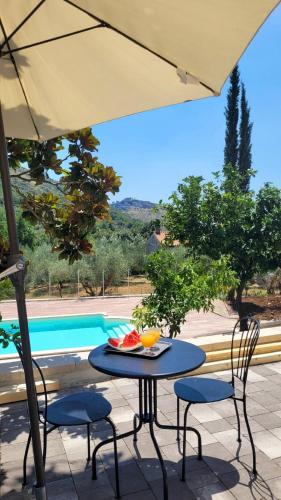 a table and chairs with an umbrella and a pool at Villa MaVi Guesthouse in Maenza