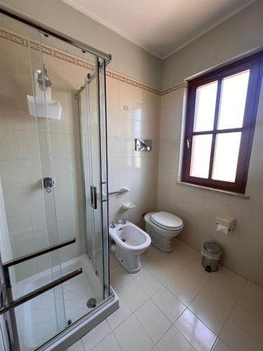 a bathroom with a toilet and a glass shower at Borgo nuovo in Donigala Fenughedu