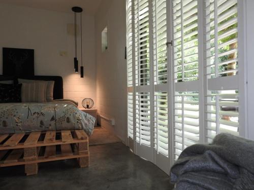 a bedroom with white plantation shuttered windows and a bed at Casa Milo in Lokeren
