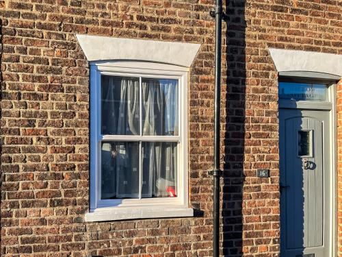 a brick building with a window and a blue door at Willow Cottage in Beverley