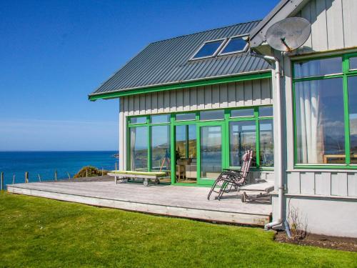 a house with a deck with a bench and the ocean at Longa House in Big Sand