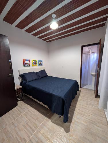 a bedroom with a bed with a blue bedspread at Casa Jardim 2 in Miguel Pereira