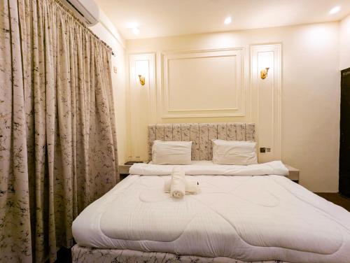 1 Schlafzimmer mit 2 Betten mit weißer Bettwäsche und Vorhängen in der Unterkunft White Rose BnB Family - Near Millennium Mall - Airport - National Stadium in Karatschi