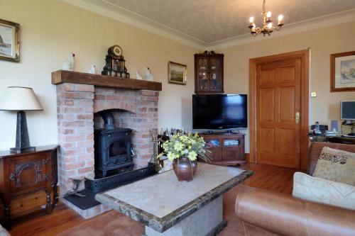 a living room with a brick fireplace and a television at Brae-Mar B&B in Portrush