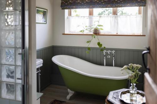 a green bath tub in a bathroom with a window at Husk in Thorington