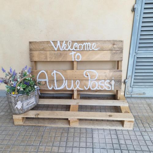 a wooden bench with a welcome to a dogoss sign at A due passi in Certaldo