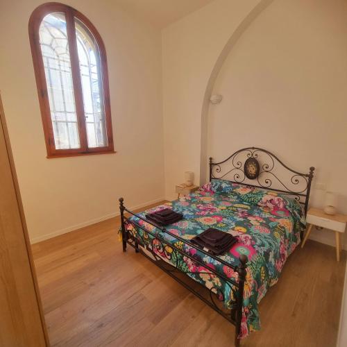 a bedroom with a bed with a floral bedspread and a window at A due passi in Certaldo