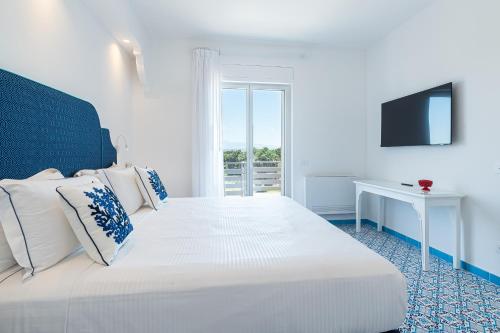 ein weißes Schlafzimmer mit einem weißen Bett und einem Fenster in der Unterkunft Lea Residenza Mediterranea Paestum in Paestum