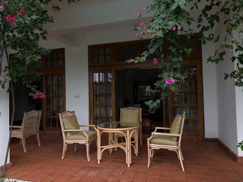 a patio with a table and chairs and flowers at Madarisha House in Kilifi