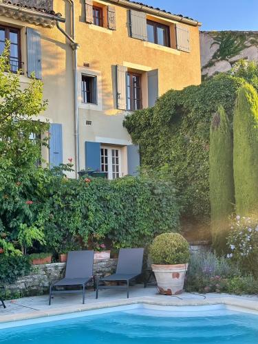- deux chaises et une piscine en face d'un bâtiment dans l'établissement Hostellerie Le Beffroi, à Vaison-la-Romaine