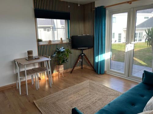 un salon avec un canapé, une table et une télévision dans l'établissement The Cosy Cabin, à Pembrokeshire