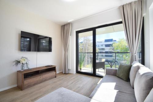 a living room with a couch and a tv at Shellter Rogowo 117J Apartamenty przy Morzu ATK in Rogowo