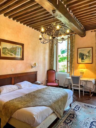 une chambre avec un lit, une table et des chaises dans l'établissement Hostellerie Le Beffroi, à Vaison-la-Romaine