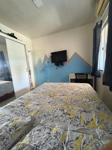 a bedroom with a large bed with a tv on the wall at Casa na Villa Sorriso in Belém
