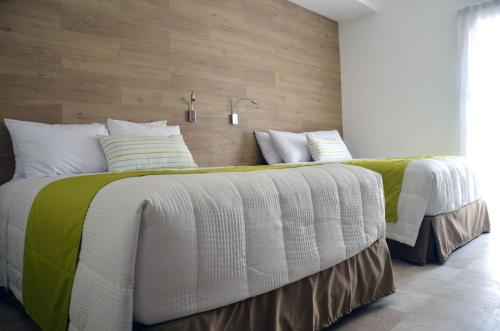 two beds with white and green comforters in a bedroom at Hotel Catedral La Paz in La Paz