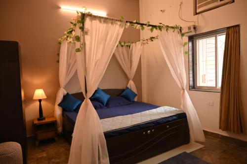 a bedroom with a canopy bed with curtains at The MiNi Nest in Gurgaon