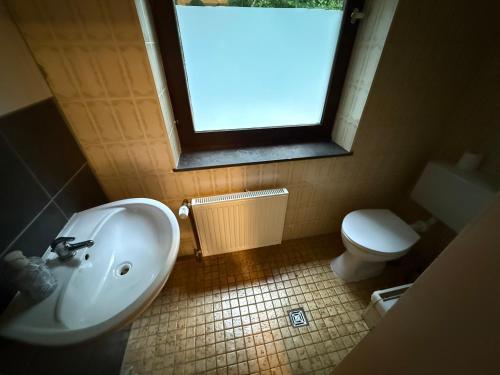 a bathroom with a sink and a toilet and a window at Pension Kalifornia Zimmer 9 Doppelzimmer für 2 Personen in Osterholz-Scharmbeck in Osterholz-Scharmbeck