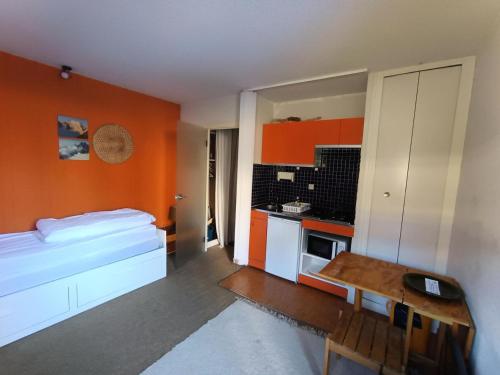 Cet appartement comprend une chambre avec un lit et une cuisine aux murs orange. dans l'établissement Résidence Arzerier - 