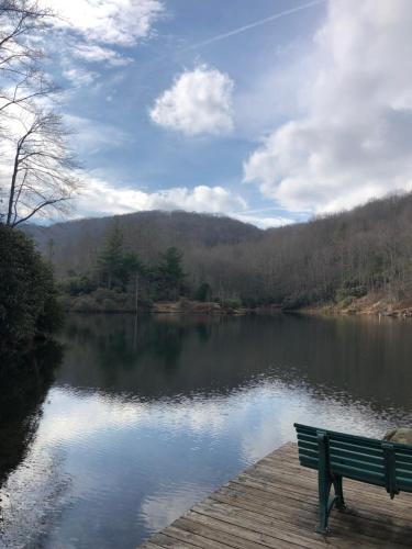 a park bench sitting on a dock next to a lake at Beech Mountain Swiss-style Chalet in Beech Mountain