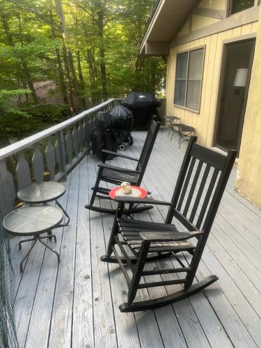two rocking chairs and a table on a porch at Beech Mountain Swiss-style Chalet in Beech Mountain