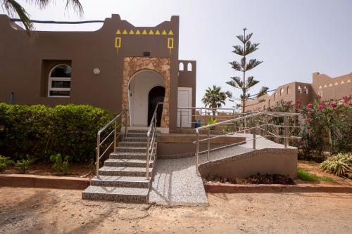 a building with a staircase leading to a door at Seabreeze 2BR Haven Ocean Walk and Sunsets in Tamellalt