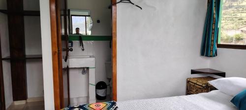 a small bedroom with a bed and a mirror at Green House Araque Inn in Otavalo