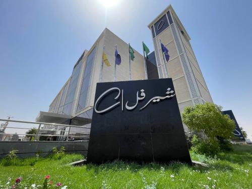 a sign in the grass in front of a building at Cheerful in Unayzah