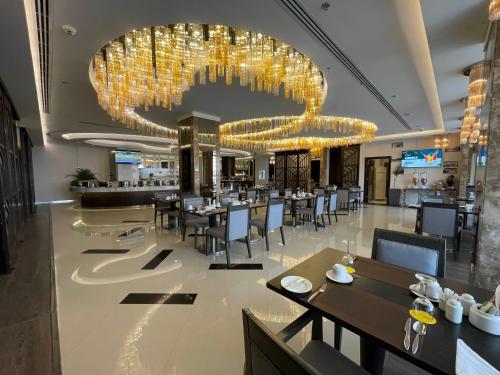 a restaurant with tables and chairs and a large chandelier at Cheerful in Unayzah