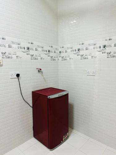 a white bathroom with a red counter and white tiles at العربي للشقق المفروشة in Salalah