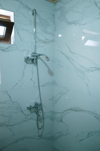 a shower in a bathroom with white marble walls at Vidikovac Dubljevici in Plužine