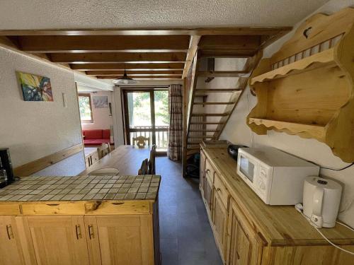 une cuisine avec des placards en bois et un comptoir avec un four micro-ondes dans l'établissement Résidence Jetay - Appartement avec mezzanine pour 7 personnes aux Ménuires MAE-4454, aux Menuires