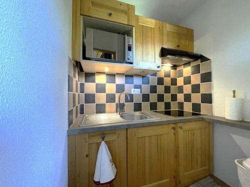 une petite cuisine avec un évier et un micro-ondes dans l'établissement Résidence Jetay - Appartement chaleureux avec vur sur la montagne MAE-4674, aux Menuires